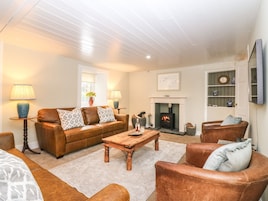 A cozy living room with a fireplace, leather sofas, and a coffee table.