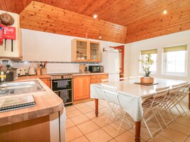 A kitchen with wooden cabinets, a stove, a microwave, and a dining area with a table and chairs.