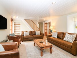A spacious living room with a wooden staircase, leather sofas, and a coffee table.