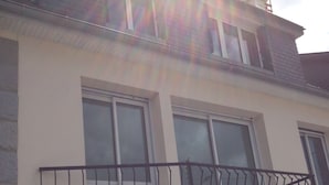 En tvåvåningsbyggnad med en balkong som har ett svart metallräcke.