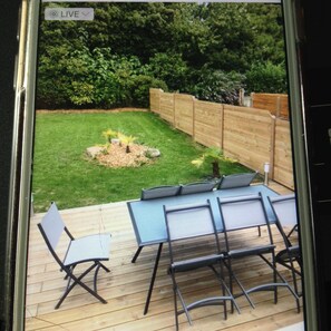 A backyard with a wooden deck, a small fire pit, and a seating area with metal chairs and a table.