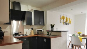 Una cocina moderna con gabinetes negros, un microondas y una estufa a gas. Hay una zona de comedor con una mesa y sillas.