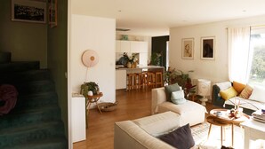 Un grand espace de vie comprenant un escalier, une cuisine à l’arrière-plan et un coin repas.