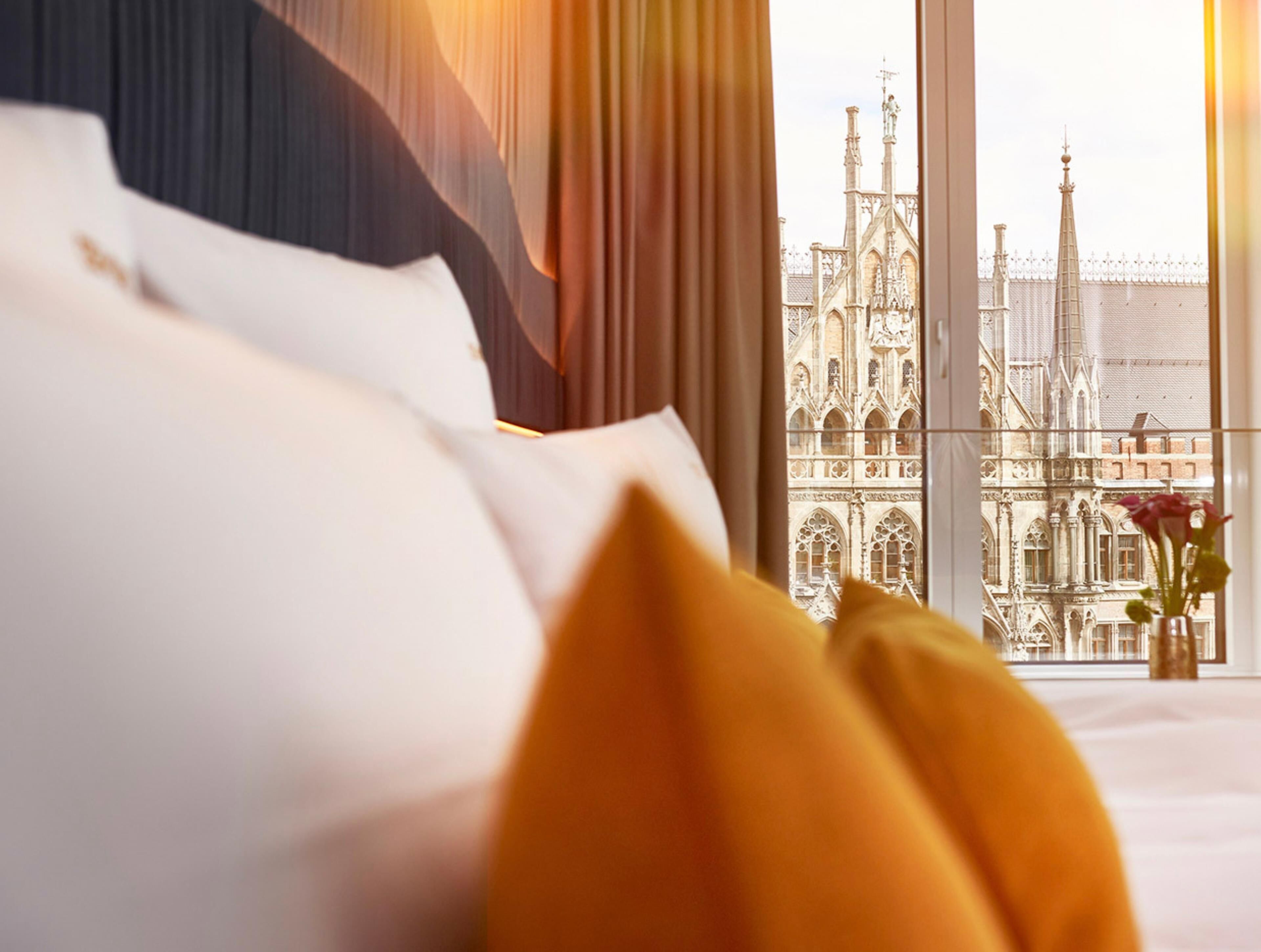 A hotel room with a large window overlooking a historic building with intricate architecture.