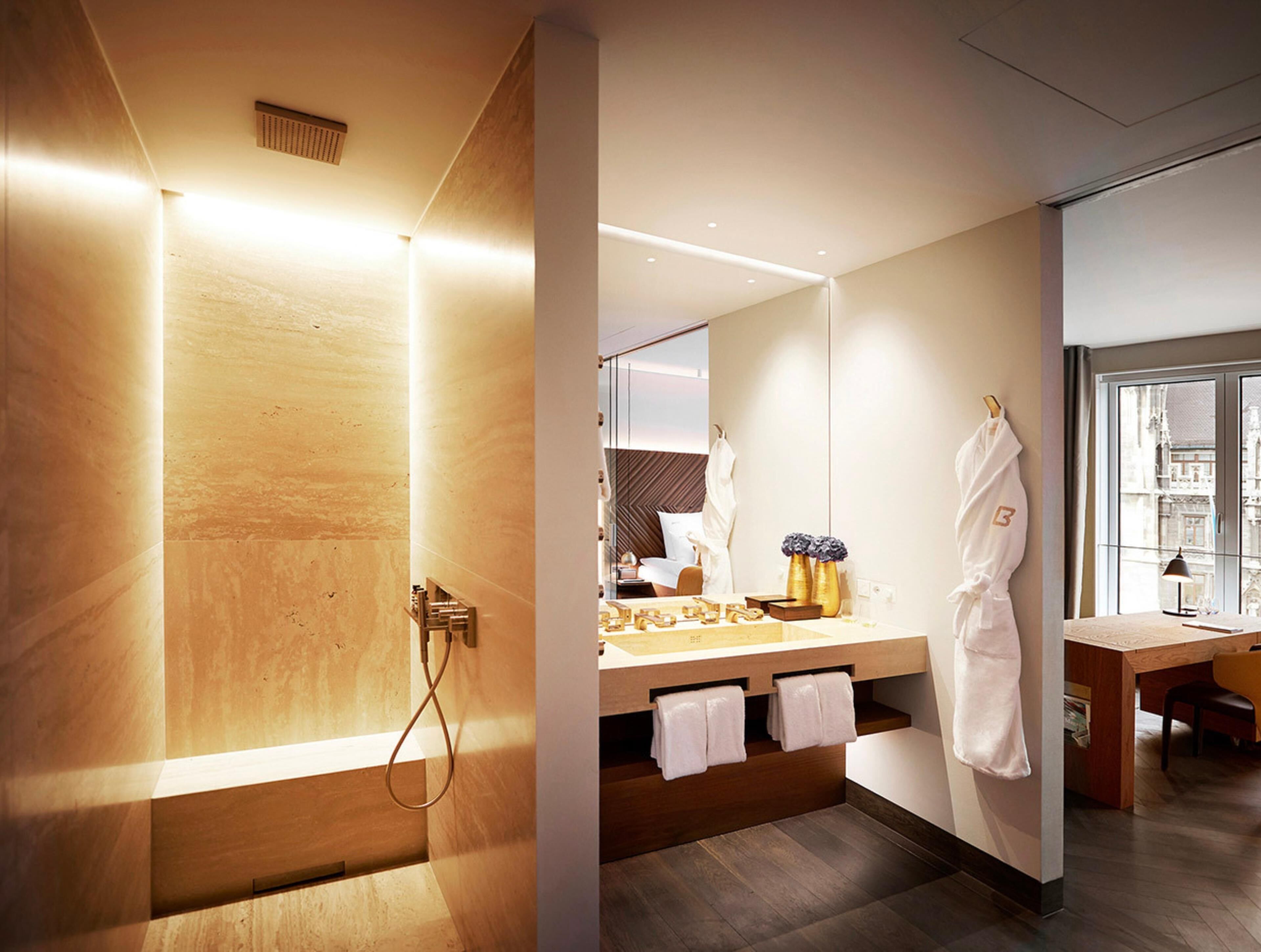 A modern bathroom with a wooden vanity, a large mirror, and a robe hanging on the wall.