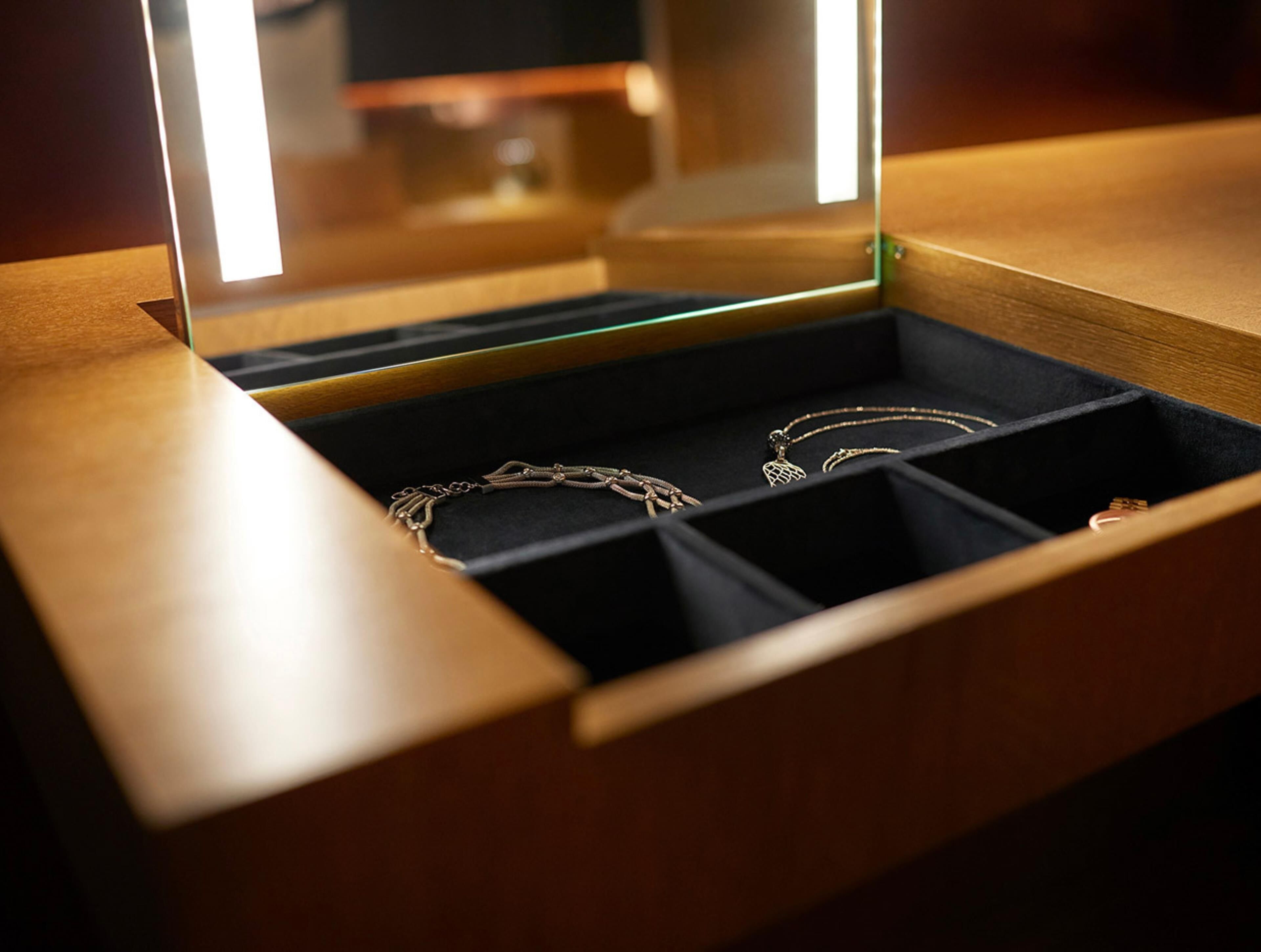 Une boîte à bijoux compartimentée, dont l’un contient un collier.