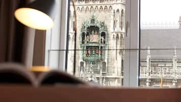 A view of a historic building with intricate architecture through a window, a lamp, and an open book.