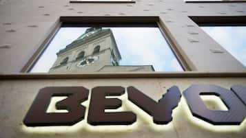 Un bâtiment doté d’une tour horlogère et dont la façade est illuminée par le mot « BEVO ».