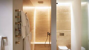 A modern bathroom with a walk-in shower, a toilet, and a towel rack.