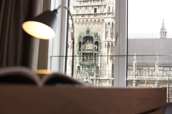 A view through a window with a lamp, showcasing a historic building with intricate architecture and a clock tower.