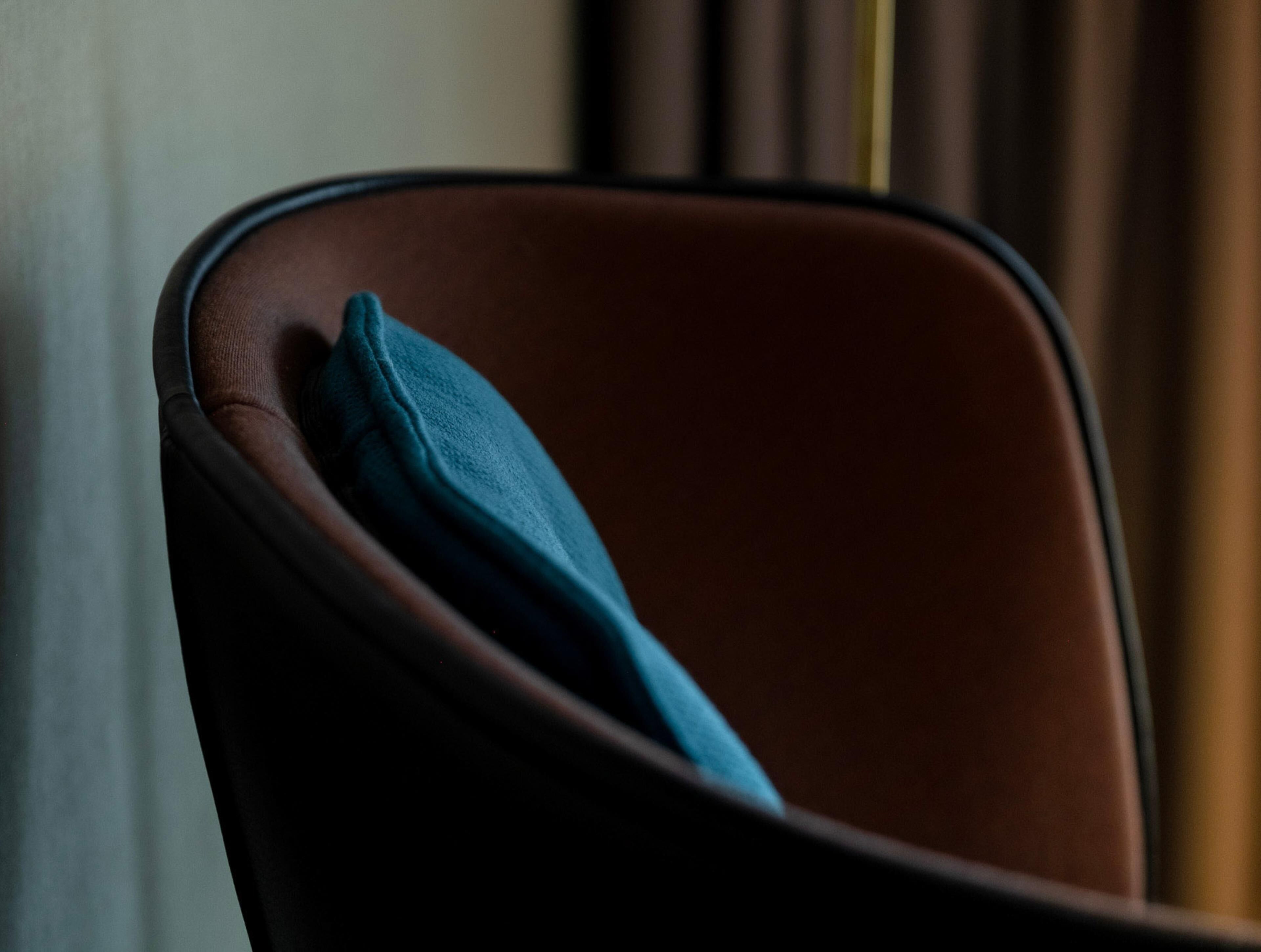 Una silla con respaldo marrón oscuro y cojín azul.