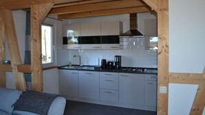 A modern kitchen with white cabinets, a black countertop, and a wooden ceiling structure. - HM- Holiday home 1 Deluxe Krombachtalsperre (Driedorf)