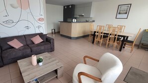 A modern living room with a sofa, coffee table, and dining area with chairs and a table.