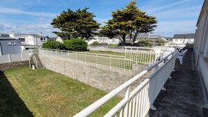 A residential area with a stone wall, a grassy lawn, and white railings.