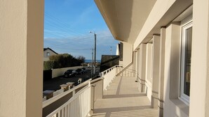 A corridor with a view of a street and parked cars.