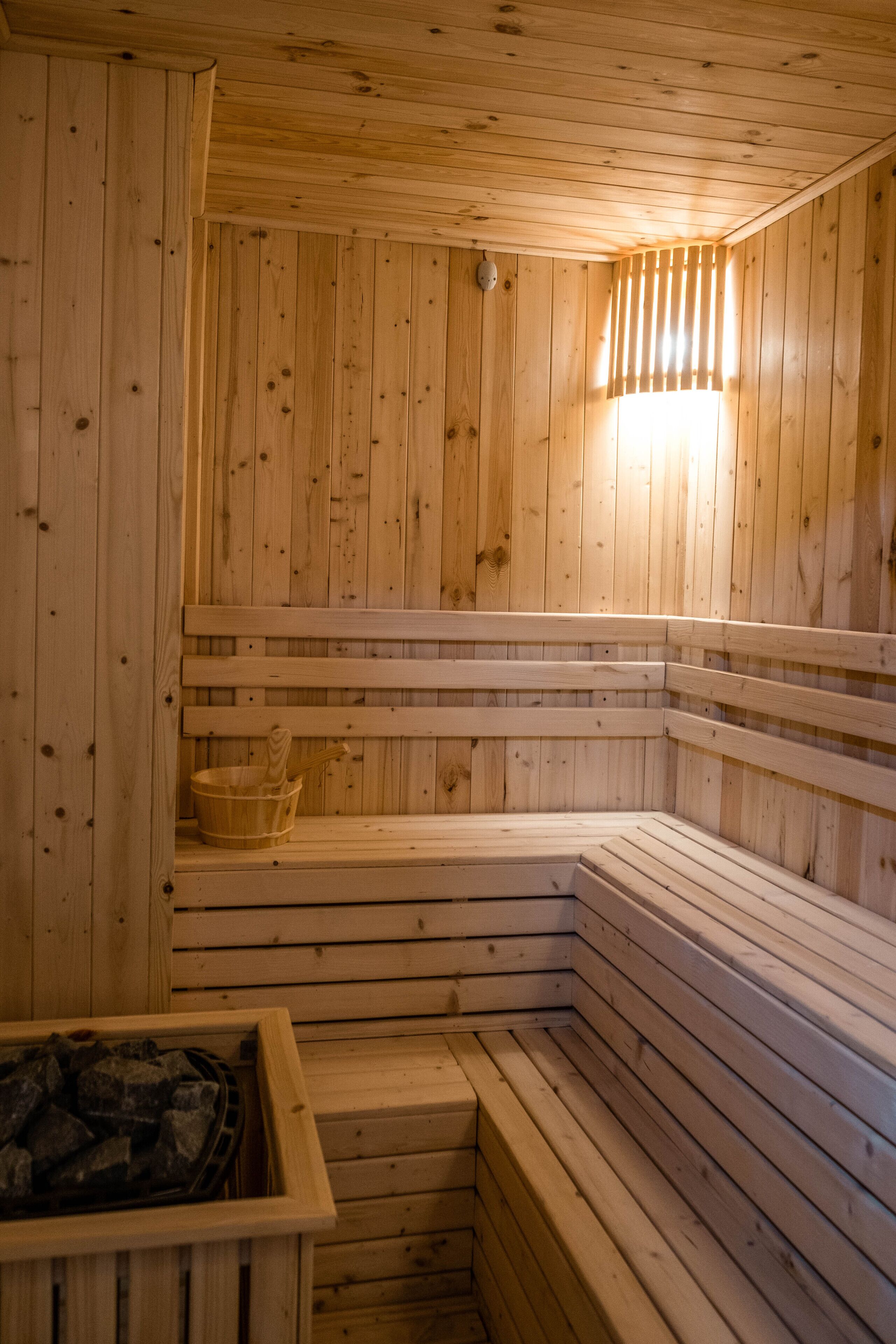 A wooden sauna with benches and a bucket.