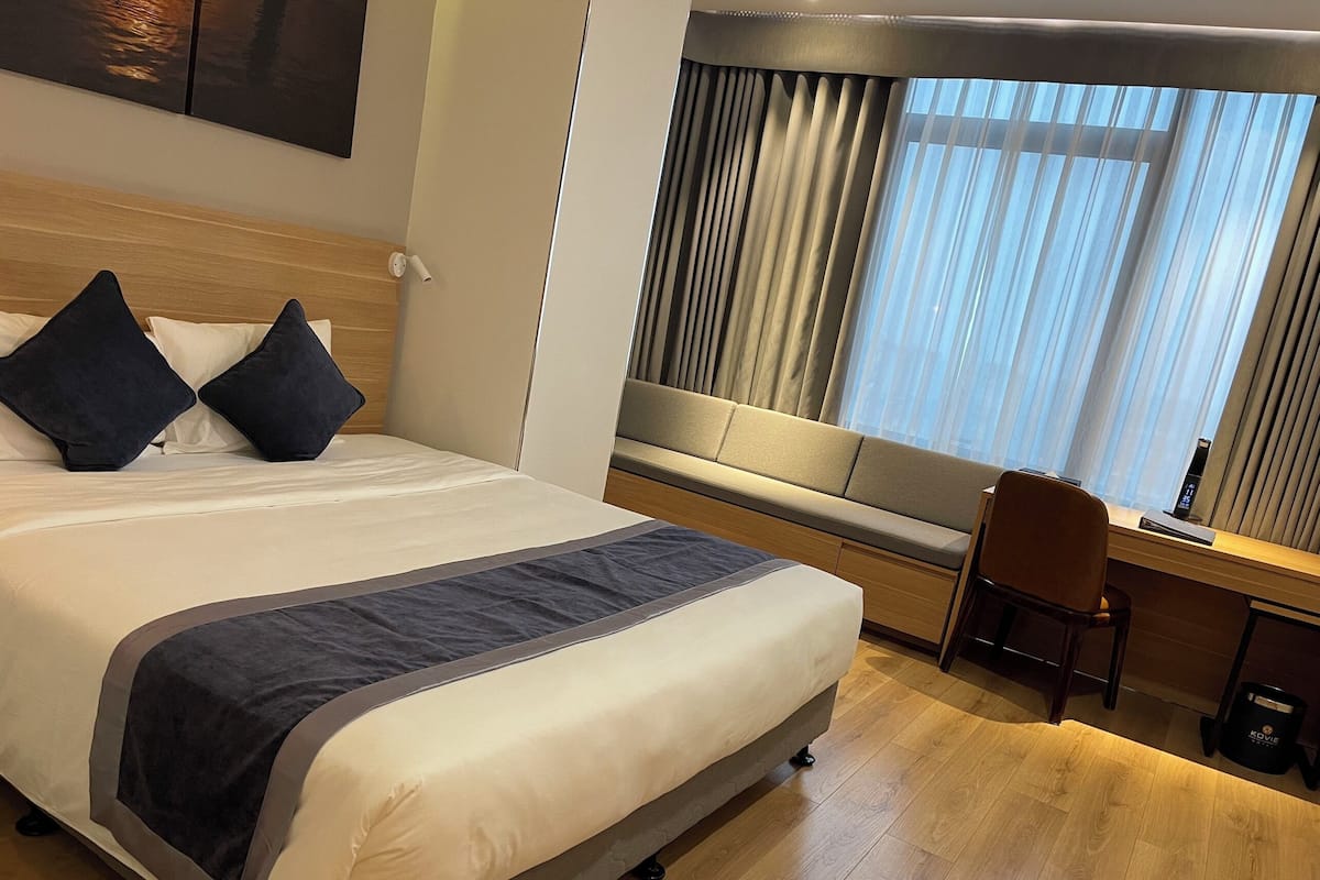 A hotel room with a large bed, a desk, and a chair.