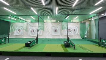 A batting cage with netting, targets, and a green turf floor.