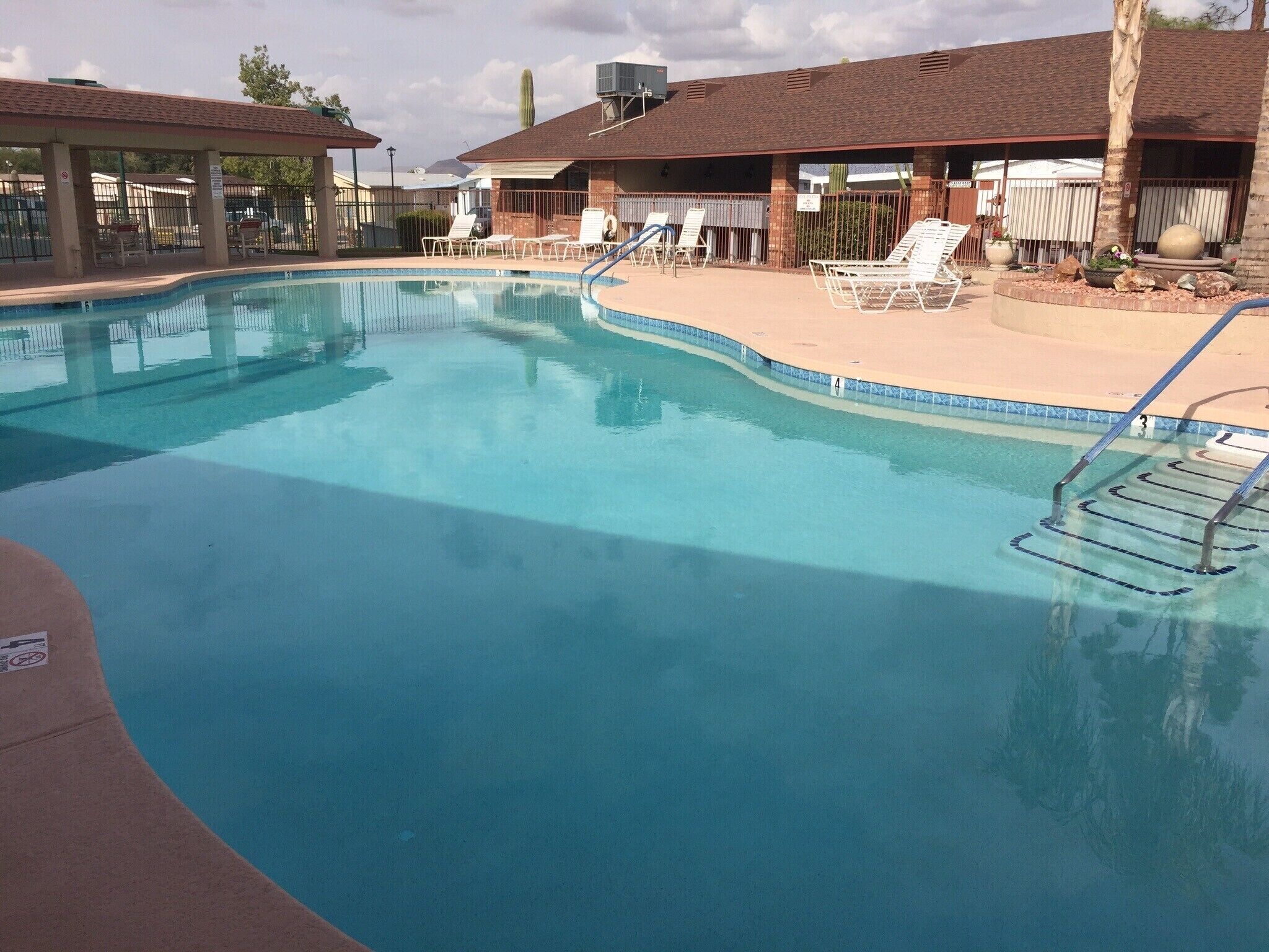 A swimming pool with lounge chairs and a lifeguard stand.