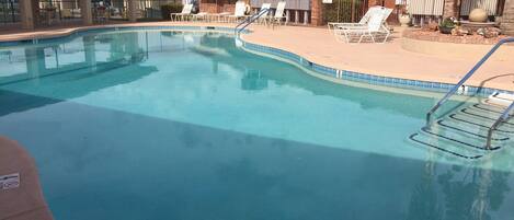A swimming pool with lounge chairs and a lifeguard stand.