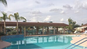Ein Schwimmbecken mit Liegestühlen und Palmen.
