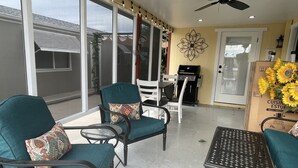 Eine Terrasse mit Türkis-farbenen Stühlen, einem Metalltisch und einem Deckenventilator.