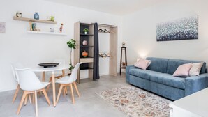 Ein modernes Wohnzimmer mit Essbereich, einem blauen Sofa und einem Gemälde an der Wand.