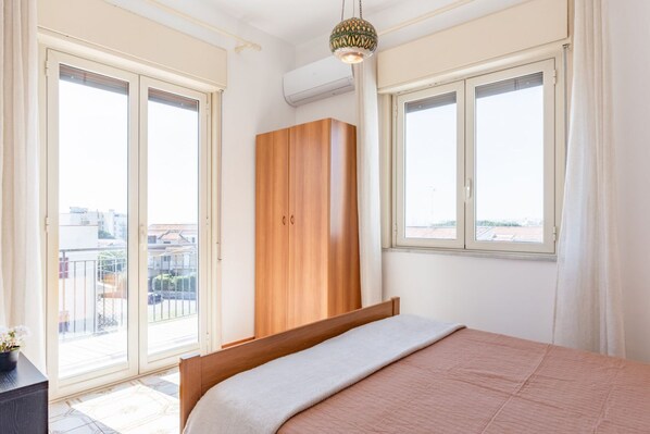 Un dormitorio con cama, armario y ventanas amplias.