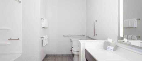 Un baño moderno con inodoro, barra de apoyo, toallero, lavabo y espejo.