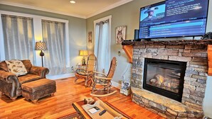 A living room with a fireplace, a television, a sofa, and a coffee table. - Experience serenity in this 3-bedroom cabin with stunning views in West Jefferson, NC. (West Jefferson)