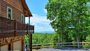 A wooden cabin with a stone foundation, a balcony, and a gravel driveway. - Experience serenity in this 3-bedroom cabin with stunning views in West Jefferson, NC. (West Jefferson)