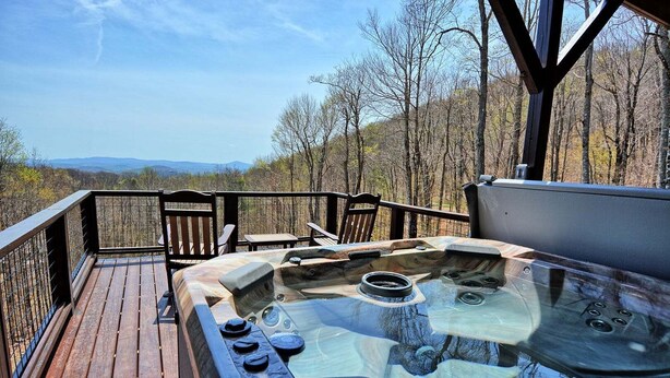 A hot tub on a wooden deck with a view of trees and mountains. - Experience serenity in this 3-bedroom cabin with stunning views in West Jefferson, NC. (West Jefferson)