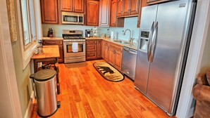 A kitchen with wooden cabinets, stainless steel appliances, and a wooden floor. - Experience serenity in this 3-bedroom cabin with stunning views in West Jefferson, NC. (West Jefferson)