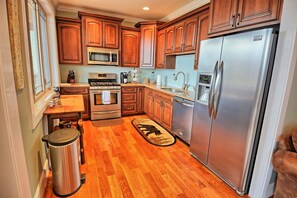 Una cocina con armarios de madera, electrodomésticos de acero inoxidable y suelo de madera.
