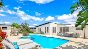 A backyard with a swimming pool, lounge chairs, and outdoor furniture.