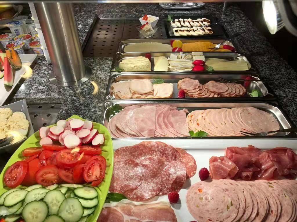 Un bufé con diferentes opciones de comida, como carnes cortadas, quesos y verduras.