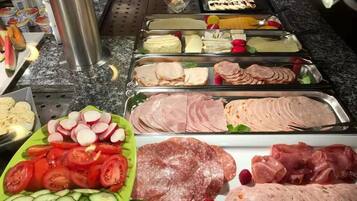 Un bufé con diferentes opciones de comida, como carnes cortadas, quesos y verduras.
