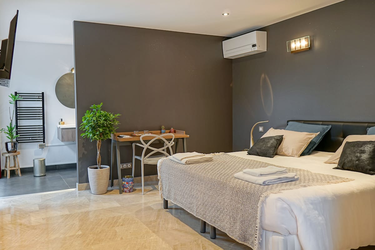 Un dormitorio moderno con cama, mesitas de noche, un escritorio y una planta en maceta.
