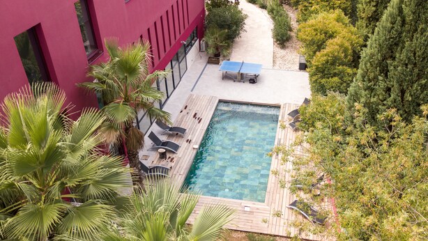 A rooftop pool with a wooden deck, lounge chairs, and a ping pong table. - Villa Magnolia (Montpellier)