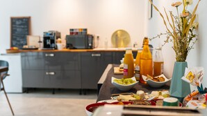 A modern kitchen with a dining area, featuring a counter with food items, a coffee machine, and a vase with flowers. - Villa Magnolia (Montpellier)