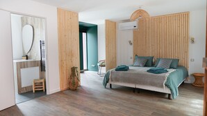 A modern bedroom with a bed, a wooden headboard, a bedside table, a mirror, and a wicker chair. - Villa Magnolia (Montpellier)