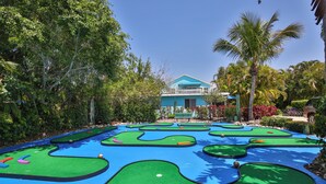 Un campo da minigolf con una casa sullo sfondo.