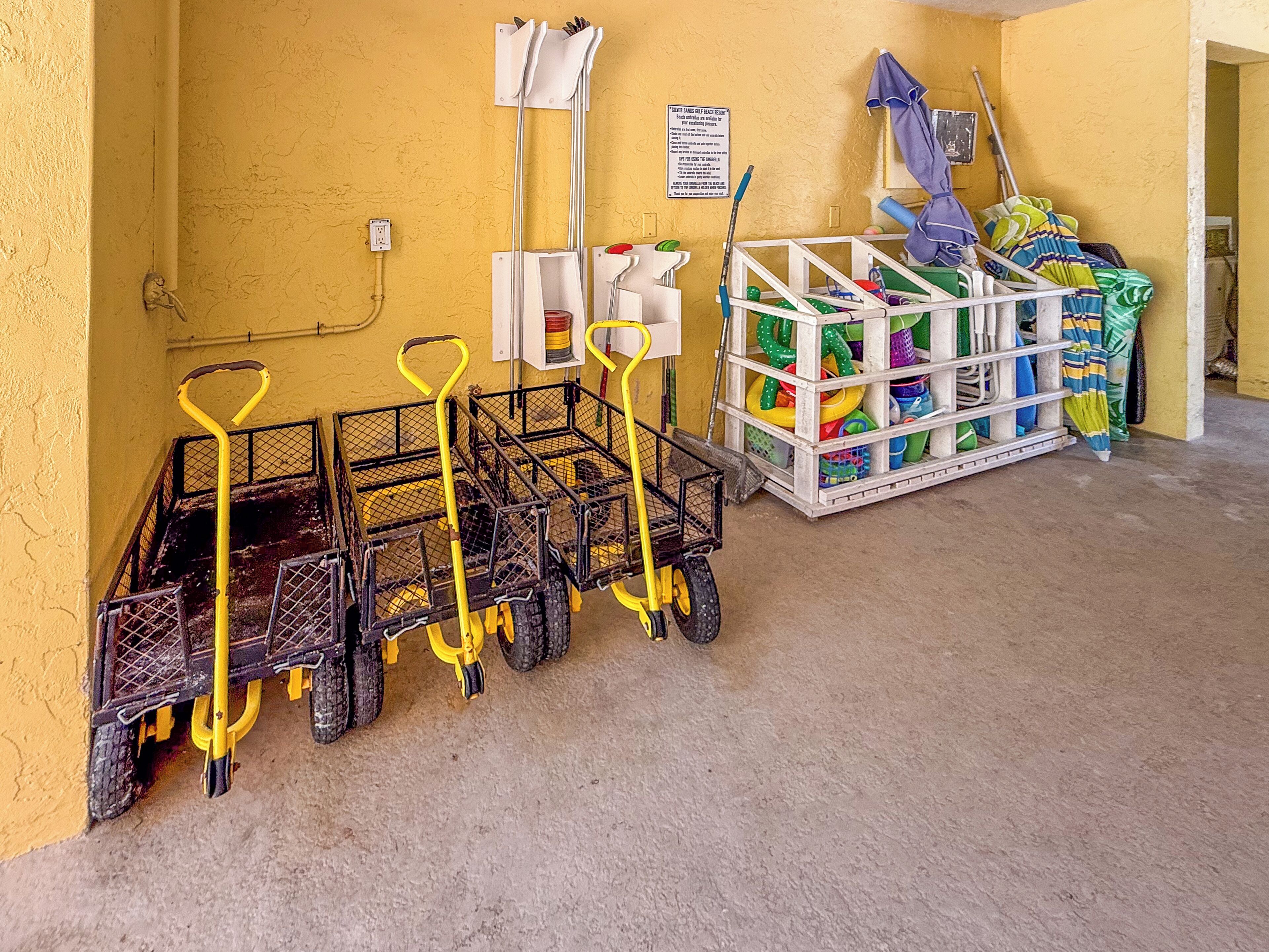 A utility cart with a mop and broom, a storage rack with cleaning supplies, and a sign on the wall.