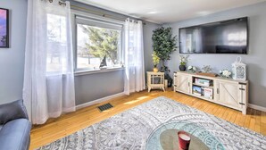 A living room with a large window, a flat-screen TV, a wooden cabinet, and a patterned rug. - Ocean Inlet Cottage w/ Deck & Grill! (West, Bath)