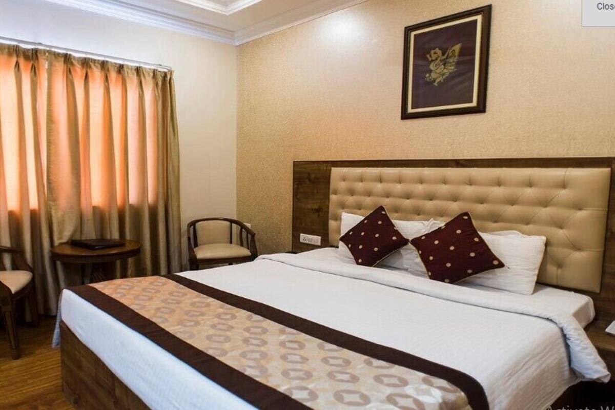 A hotel room with a large bed, two chairs, a small table, and a framed picture on the wall.