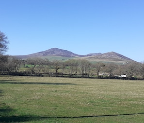 A grassy field with a mountain in the background. - Inviting 3-bed Cottage Close to Pwllheli (Pwllheli)