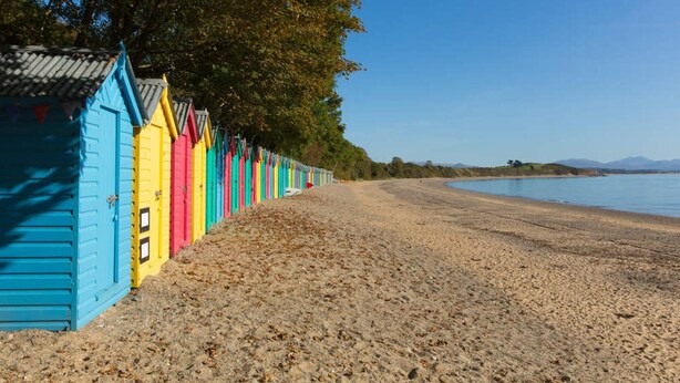 A beach with colorful beach huts and a clear sky. - Inviting 3-bed Cottage Close to Pwllheli (Pwllheli)