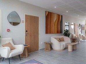 A modern hotel lobby with a sofa, chairs, a wooden door, and a large abstract painting. - ibis Styles Amiens Sud (Amiens)