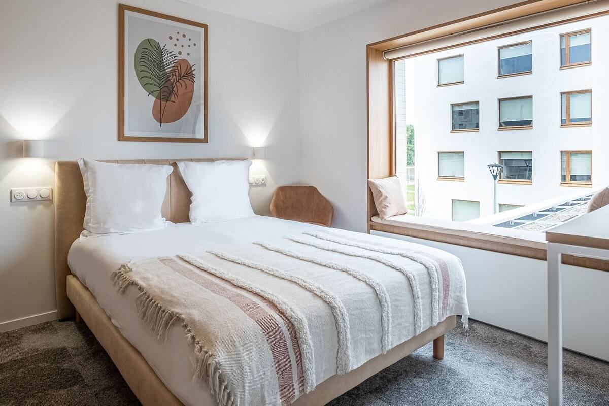 Ein Schlafzimmer mit einem Bett, einem Fenster und einem Wandbild.
