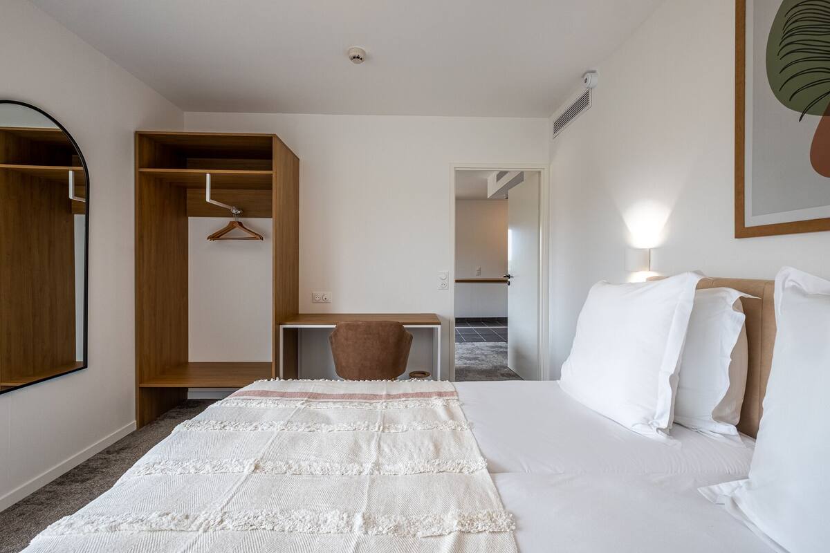 Ein Hotelzimmer mit Bett, Schreibtisch, Stuhl und Kleiderschrank.